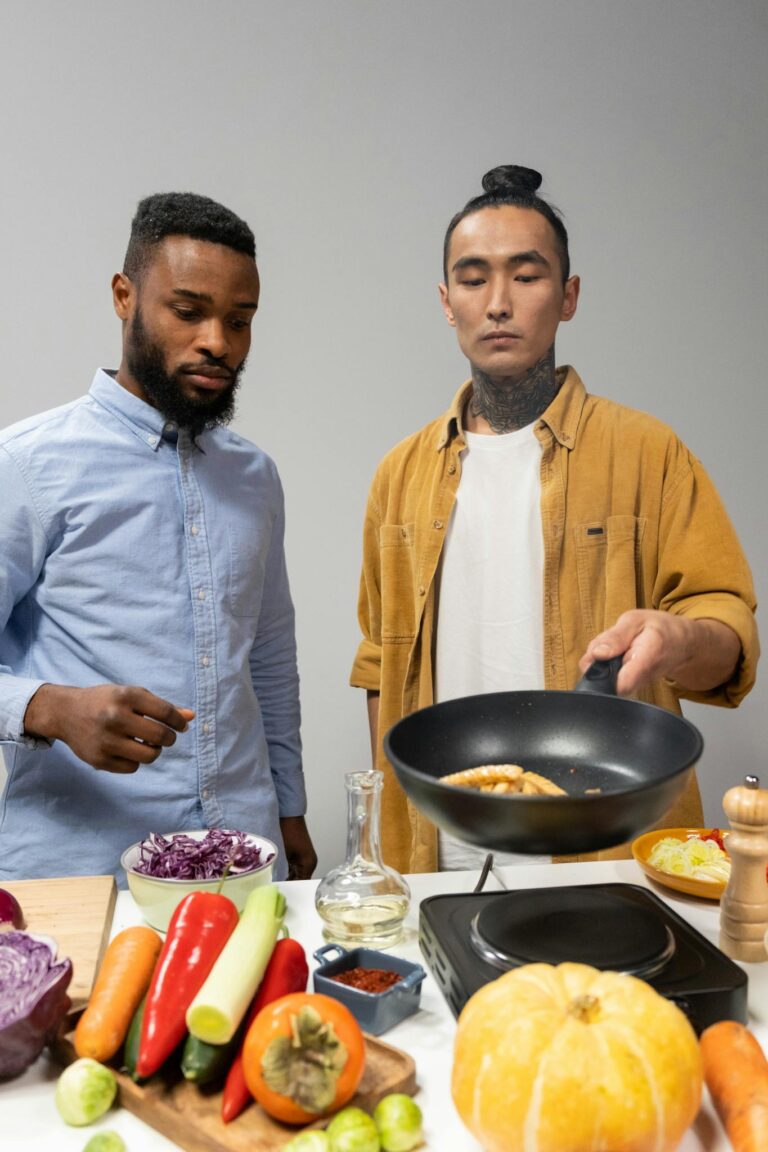 Two chefs collaborating in a kitchen while preparing a variety of fresh ingredients.